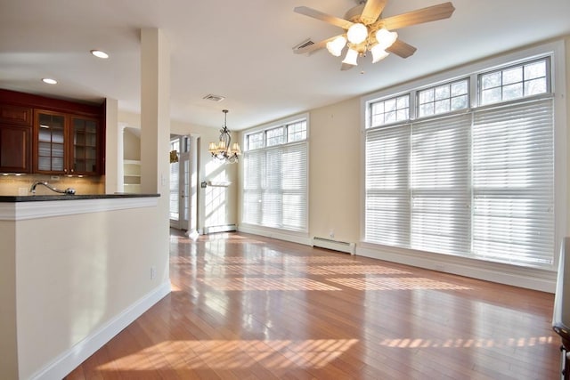 unfurnished dining area featuring a baseboard heating unit, baseboard heating, light wood-type flooring, and visible vents