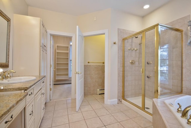 bathroom featuring a walk in closet, tile patterned floors, a garden tub, and vanity