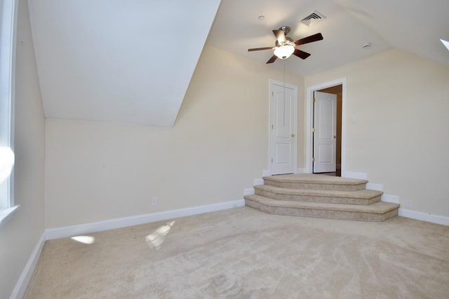 interior space featuring carpet, visible vents, a ceiling fan, vaulted ceiling, and baseboards