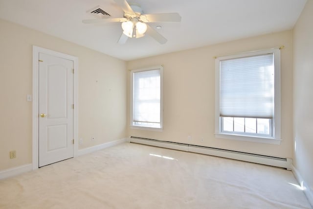 empty room with a baseboard heating unit, light colored carpet, visible vents, and baseboards