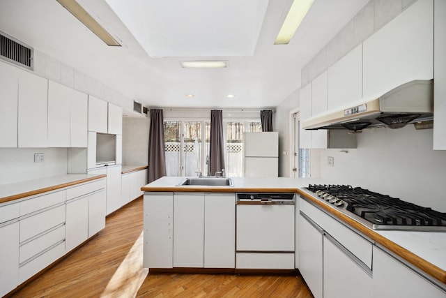 kitchen with sink, white cabinetry, light hardwood / wood-style flooring, kitchen peninsula, and white appliances