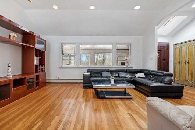 living room with a baseboard radiator, lofted ceiling with skylight, and light wood-type flooring