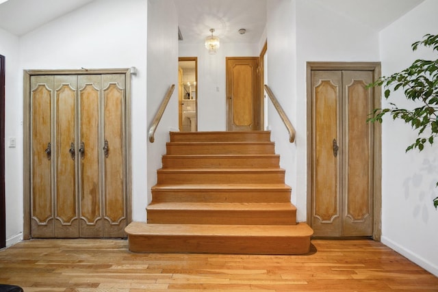 staircase featuring hardwood / wood-style flooring and lofted ceiling