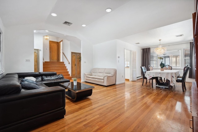 living room featuring lofted ceiling, a baseboard heating unit, and light hardwood / wood-style floors