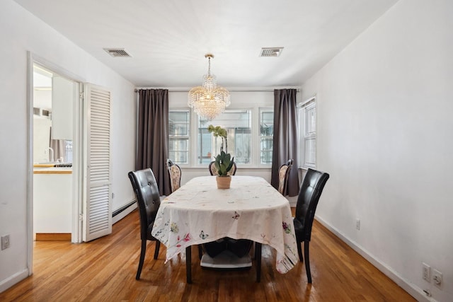 dining room featuring a baseboard heating unit, light hardwood / wood-style flooring, and a chandelier