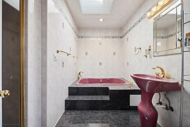 bathroom featuring tile walls, sink, and a relaxing tiled tub