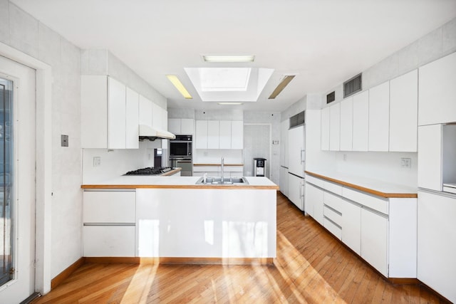 kitchen with sink, stainless steel appliances, kitchen peninsula, and white cabinets