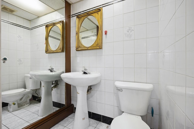 bathroom with tile patterned floors, toilet, and tile walls