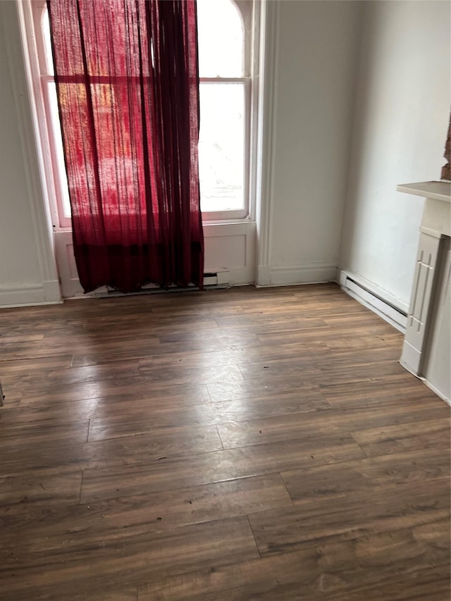 empty room with baseboard heating and dark wood-type flooring