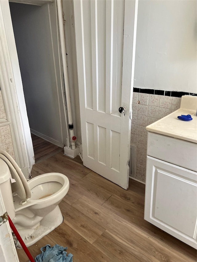 bathroom featuring tile walls, hardwood / wood-style flooring, and toilet