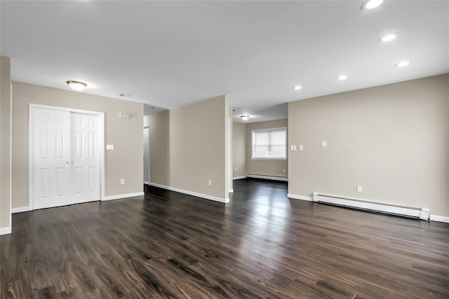 empty room with dark hardwood / wood-style flooring and baseboard heating