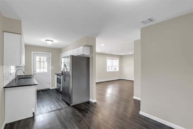 kitchen featuring dark wood-type flooring, sink, baseboard heating, appliances with stainless steel finishes, and white cabinets