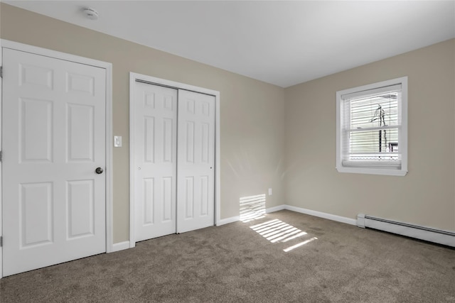 unfurnished bedroom with carpet flooring, a closet, and a baseboard heating unit