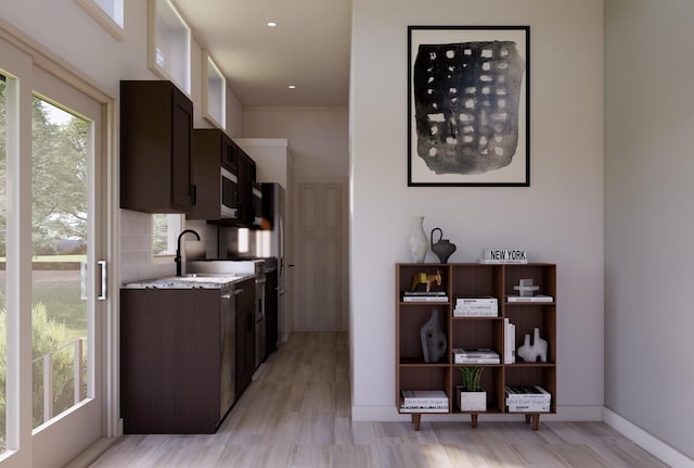 kitchen featuring sink, light stone counters, dark brown cabinetry, and light hardwood / wood-style floors