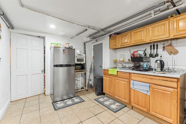 kitchen featuring light tile patterned flooring, sink, stainless steel appliances, and tasteful backsplash