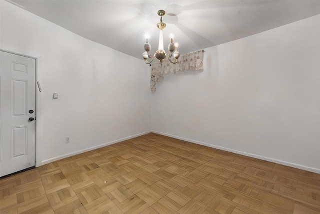 empty room with light parquet flooring and a chandelier