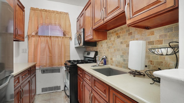 kitchen with appliances with stainless steel finishes, radiator, sink, backsplash, and light tile patterned floors