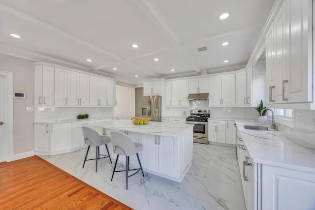 kitchen with sink, a breakfast bar area, a center island, stainless steel appliances, and white cabinets