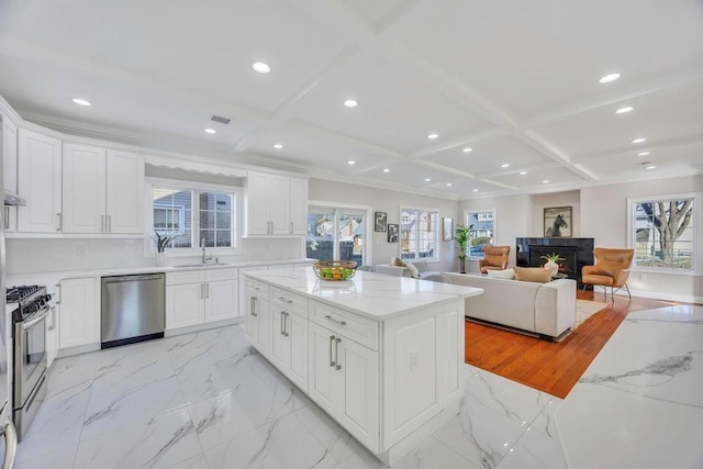 kitchen featuring white cabinetry, appliances with stainless steel finishes, coffered ceiling, and light stone countertops