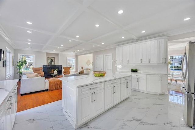 kitchen with stainless steel refrigerator, white cabinetry, coffered ceiling, and a kitchen island