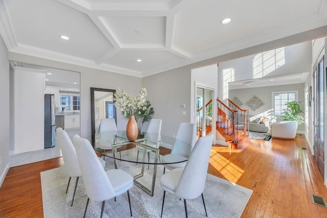 dining space with crown molding, coffered ceiling, and light hardwood / wood-style floors