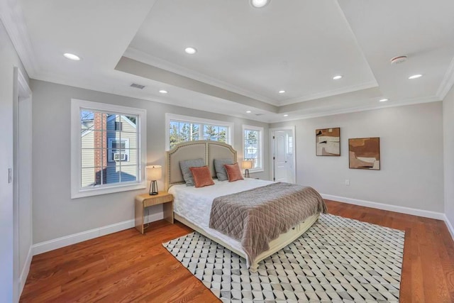 bedroom with hardwood / wood-style flooring, a tray ceiling, and crown molding