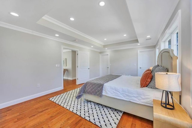 bedroom featuring crown molding, a tray ceiling, and wood-type flooring