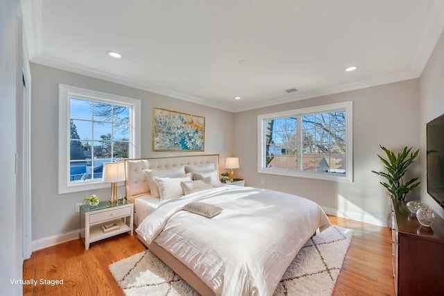 bedroom with ornamental molding, light hardwood / wood-style floors, and multiple windows