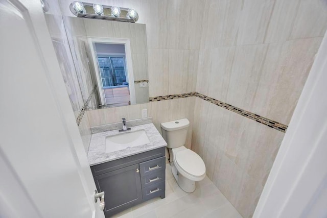 bathroom with vanity, tile walls, tile patterned floors, and toilet