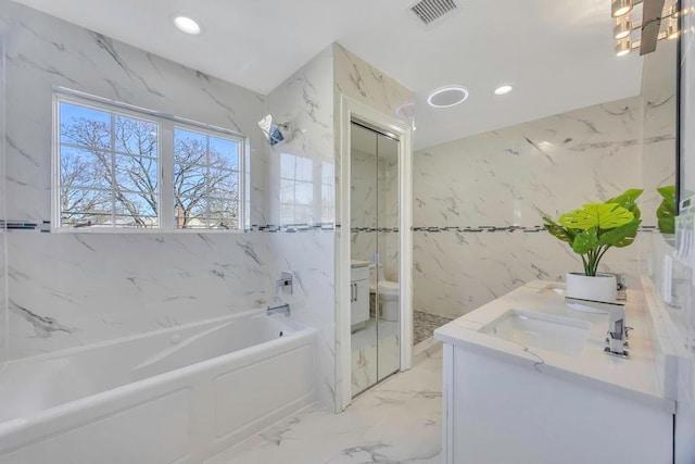 bathroom with tile walls, a tub to relax in, vanity, and toilet