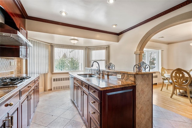 kitchen featuring ornamental molding, radiator heating unit, sink, and a kitchen island with sink