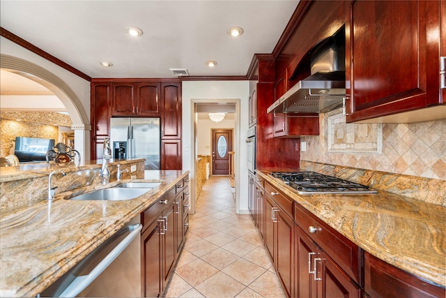 kitchen with sink, appliances with stainless steel finishes, backsplash, light stone countertops, and wall chimney exhaust hood