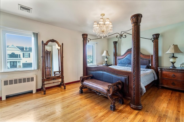 bedroom featuring radiator, a chandelier, and light wood-type flooring