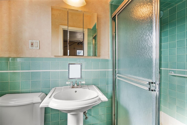 bathroom with tile walls, sink, a shower with door, and toilet