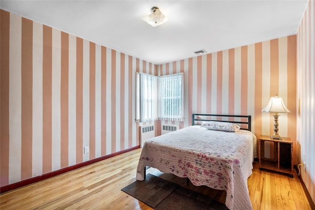 bedroom featuring radiator heating unit and light hardwood / wood-style floors