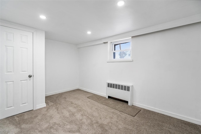 basement featuring radiator heating unit and light carpet