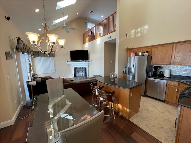 kitchen featuring appliances with stainless steel finishes, high vaulted ceiling, a skylight, a breakfast bar area, and a center island