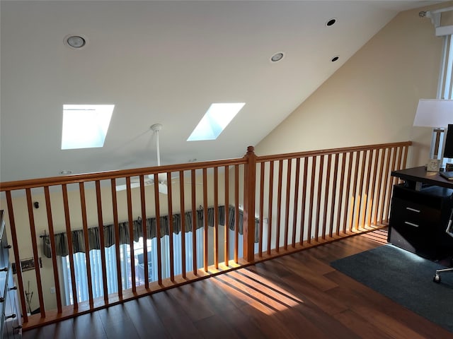 corridor with dark hardwood / wood-style flooring, a healthy amount of sunlight, and vaulted ceiling with skylight