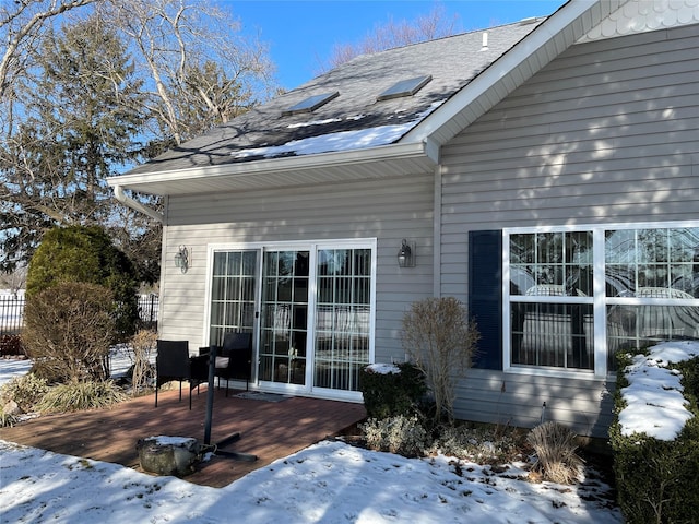 snow covered property entrance with a deck