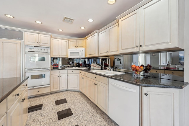 kitchen with sink, white appliances, and dark stone counters