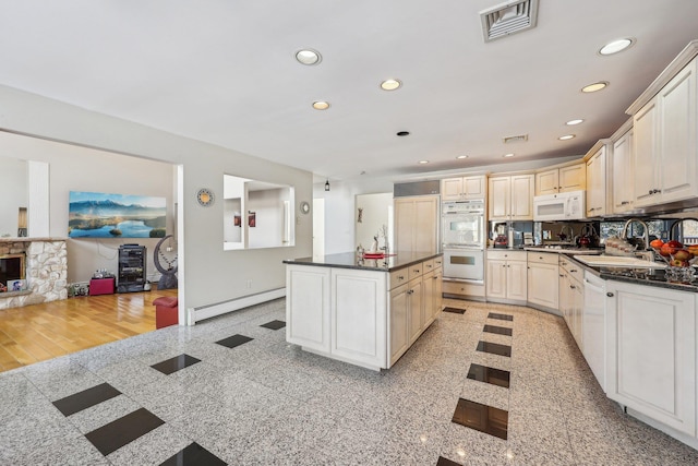 kitchen with tasteful backsplash, a center island, white appliances, a fireplace, and a baseboard heating unit