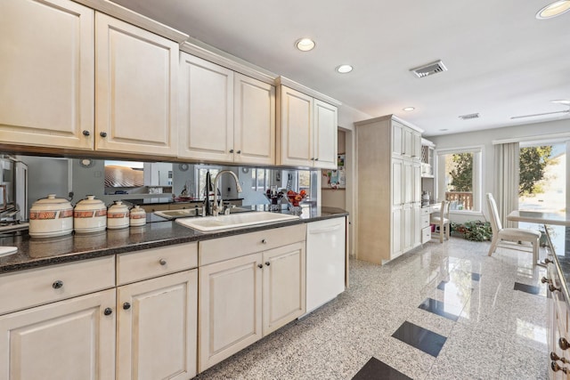 kitchen featuring sink, cream cabinets, dark stone counters, and dishwasher