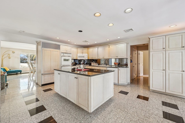 kitchen with sink, white appliances, white cabinets, and a kitchen island