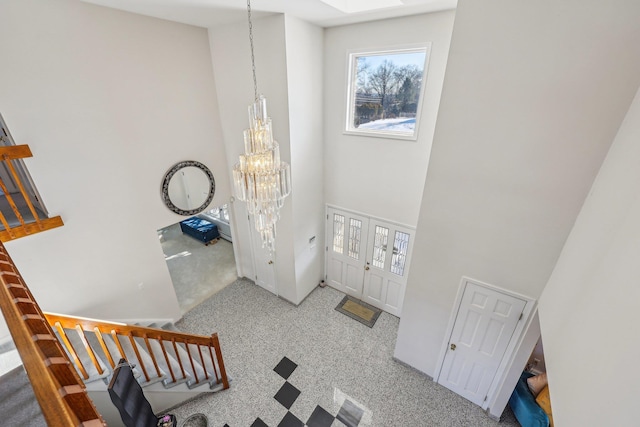 entryway with a skylight, a chandelier, and a high ceiling