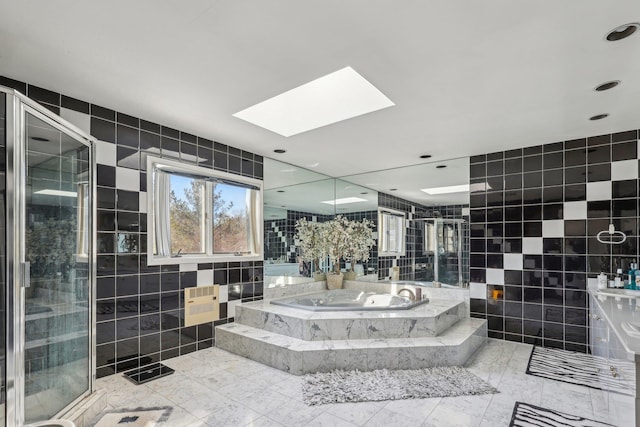 bathroom with shower with separate bathtub, tile walls, and a skylight