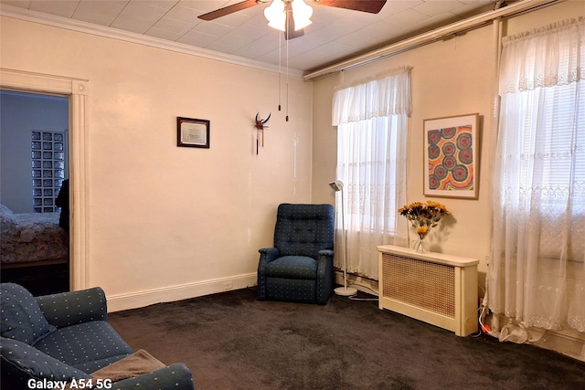 living area featuring ceiling fan, ornamental molding, radiator, and dark carpet