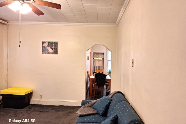 sitting room featuring ornamental molding, ceiling fan, and dark carpet