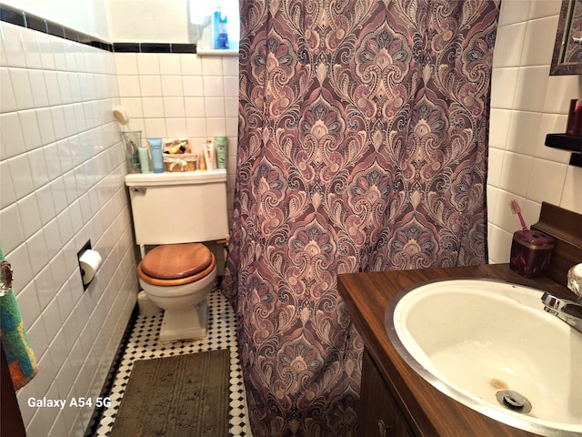 bathroom with vanity, toilet, tile patterned flooring, and tile walls