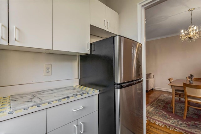 kitchen with dark wood-type flooring, a chandelier, white cabinets, and stainless steel refrigerator