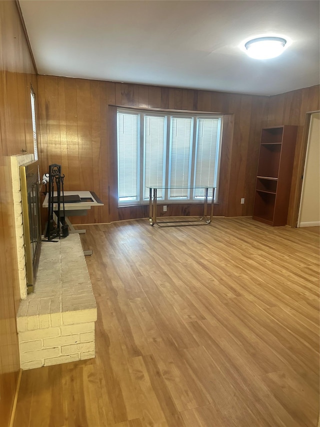 unfurnished living room with wood walls and light wood-type flooring